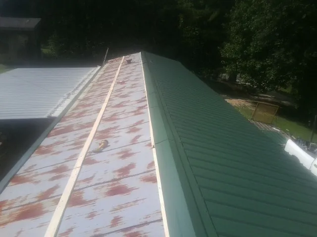 Old rusted panels beside newly installed green metal roofing — Wind Damage Roof Repair by Roofing Brothers in Canyon Lake