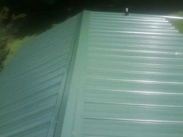 New green metal panels meeting at the ridge of a roof — Flat Roof Repair work by our crew in Canyon Lake