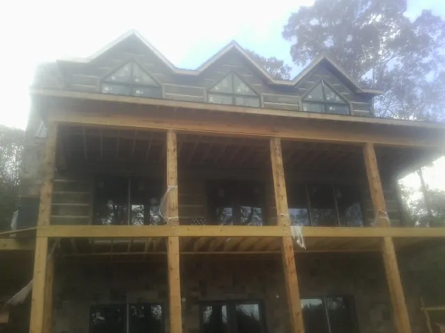 Dormers and porch framing on a large log home under construction — Roof Coating work by our crew in Canyon Lake