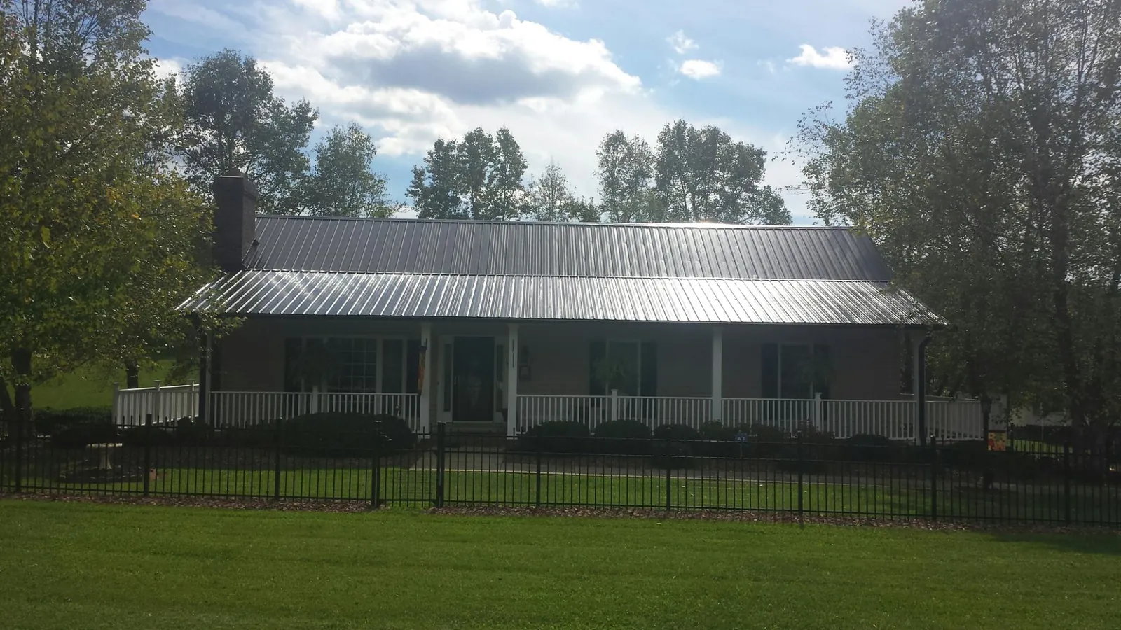 Gray metal roof on a brick ranch with a full width front porch — Gutter Guard Installation work by our crew in Canyon Lake