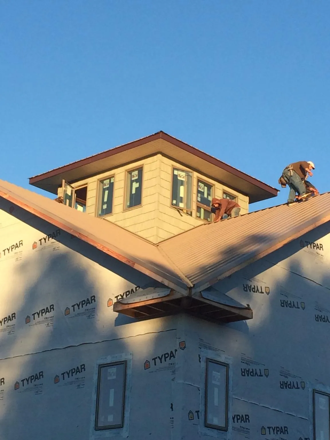 Roofers working around a rooftop cupola on a new metal roof at sunset — Roof Waterproofing in Canyon Lake by Roofing Brothers